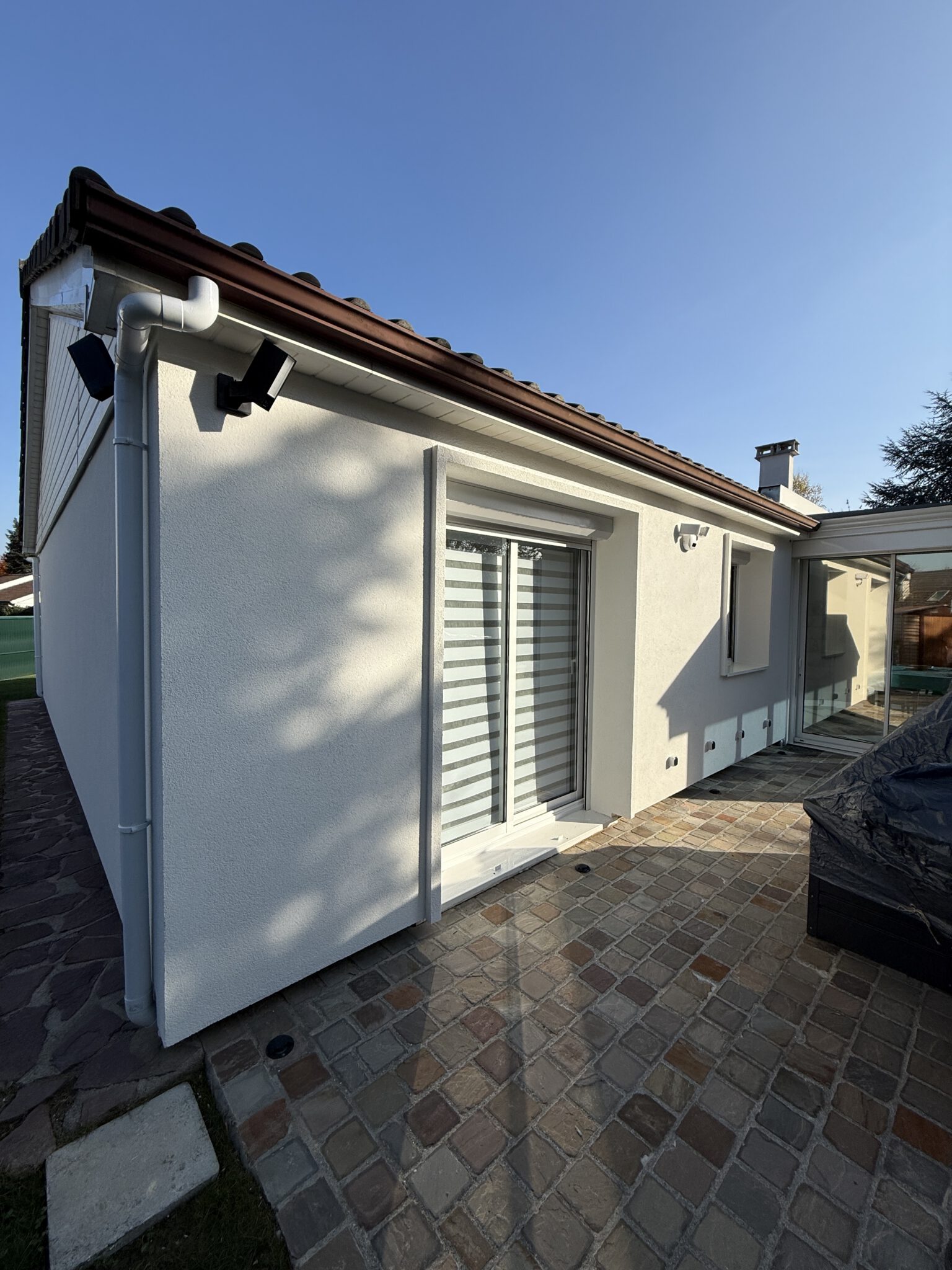 Pignon et terrasse d'un pavillon après isolation par l'extérieur, enduit blanc gratté